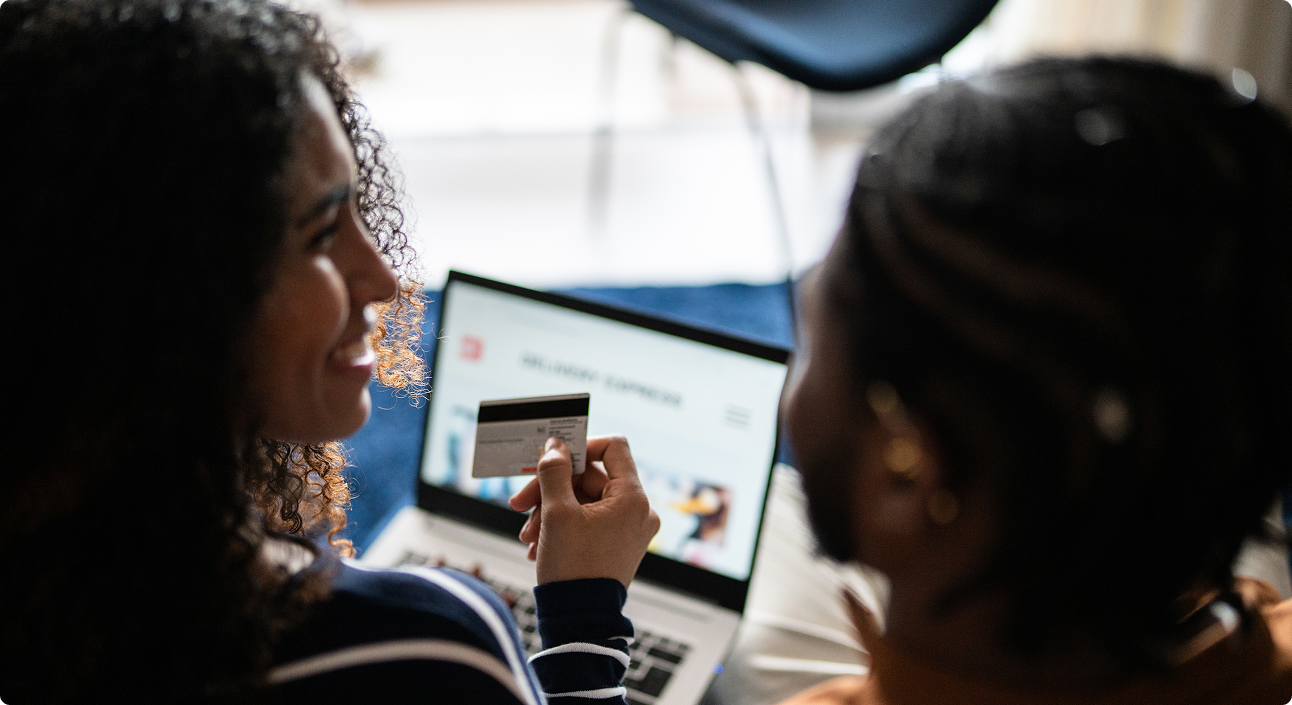 8 West Consulting - Two girls shopping online with a credit card via a laptop.
