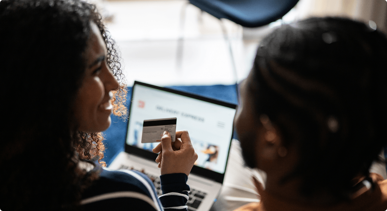 8 West Consulting - Two girls shopping online with a credit card via a laptop.